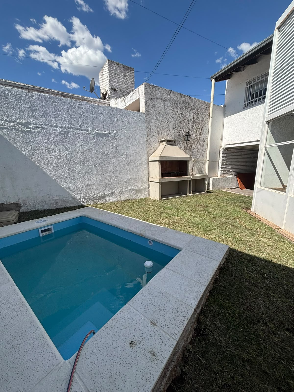 Patio con piscina y parrilla